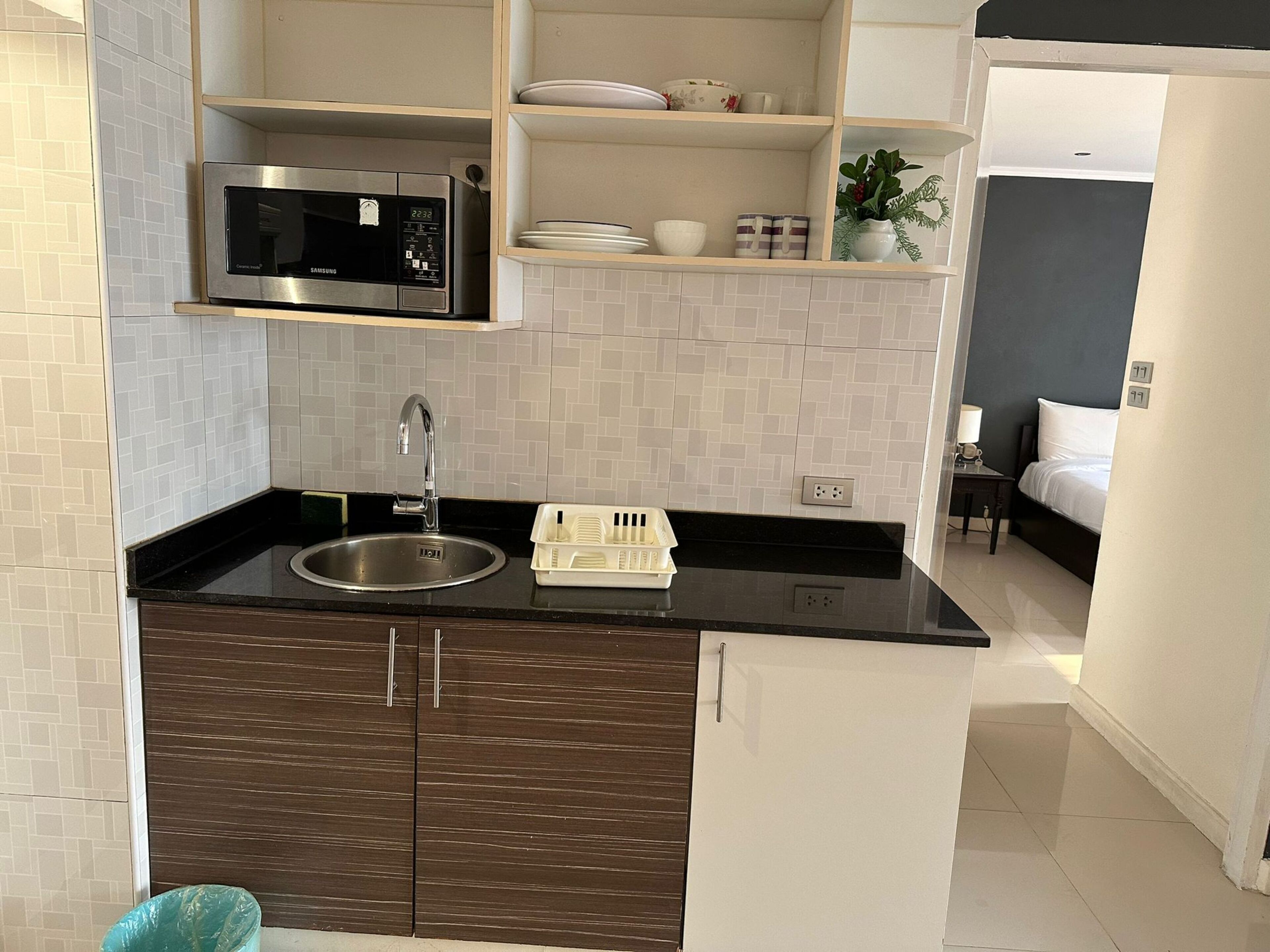 A compact kitchen with a microwave, sink, and storage cabinets.