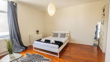 A bedroom with a bed, bedside table, lamp, and a hanging light fixture.