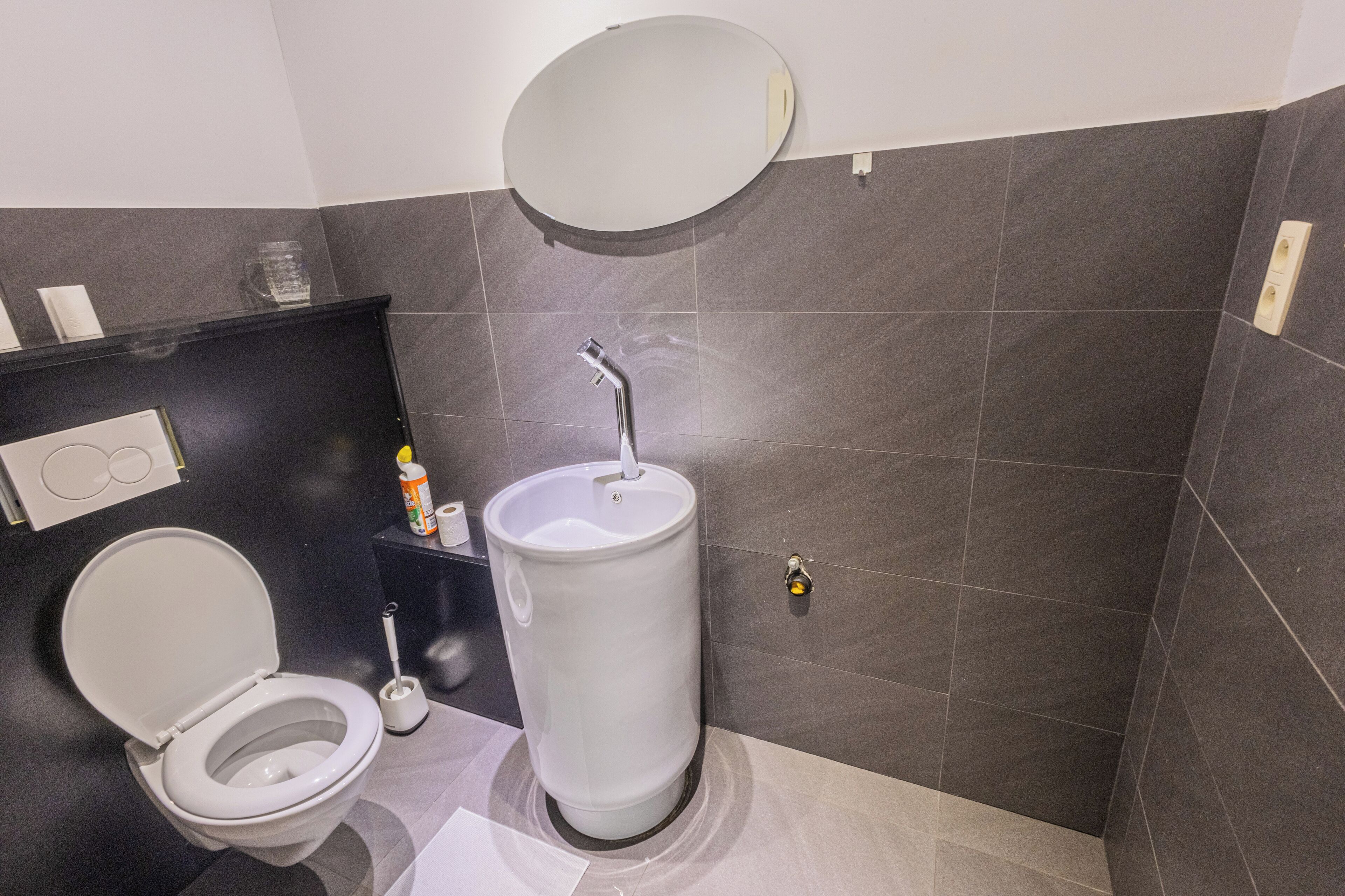 Un baño moderno con inodoro, lavabo y espejo.