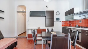 A compact kitchen with a dining table, chairs, a built-in oven, and a stove. - San Niccolò 31 - One Bedroom Apartment, Sleeps 2 (Firenze)
