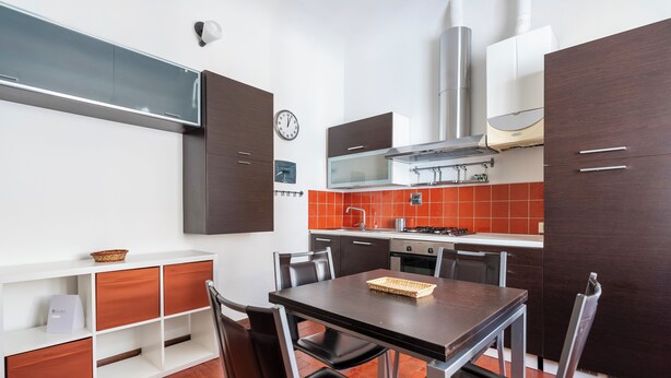A modern kitchen with a dining table, chairs, and a clock on the wall. - San Niccolò 31 - One Bedroom Apartment, Sleeps 2 (Firenze)