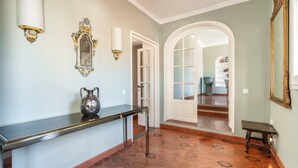 A hallway with a tiled floor, a black console table, a decorative mirror, and a wall-mounted light fixture. - Maggio 54 - Three Bedroom Apartment, Sleeps 6 (Florence)