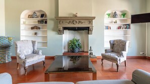 A living room with two armchairs, a coffee table, and a fireplace with decorative shelves. - Maggio 54 - Three Bedroom Apartment, Sleeps 6 (Florence)