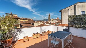 A rooftop terrace with potted plants, a table, and chairs. - Maggio 54 - Three Bedroom Apartment, Sleeps 6 (Florence)