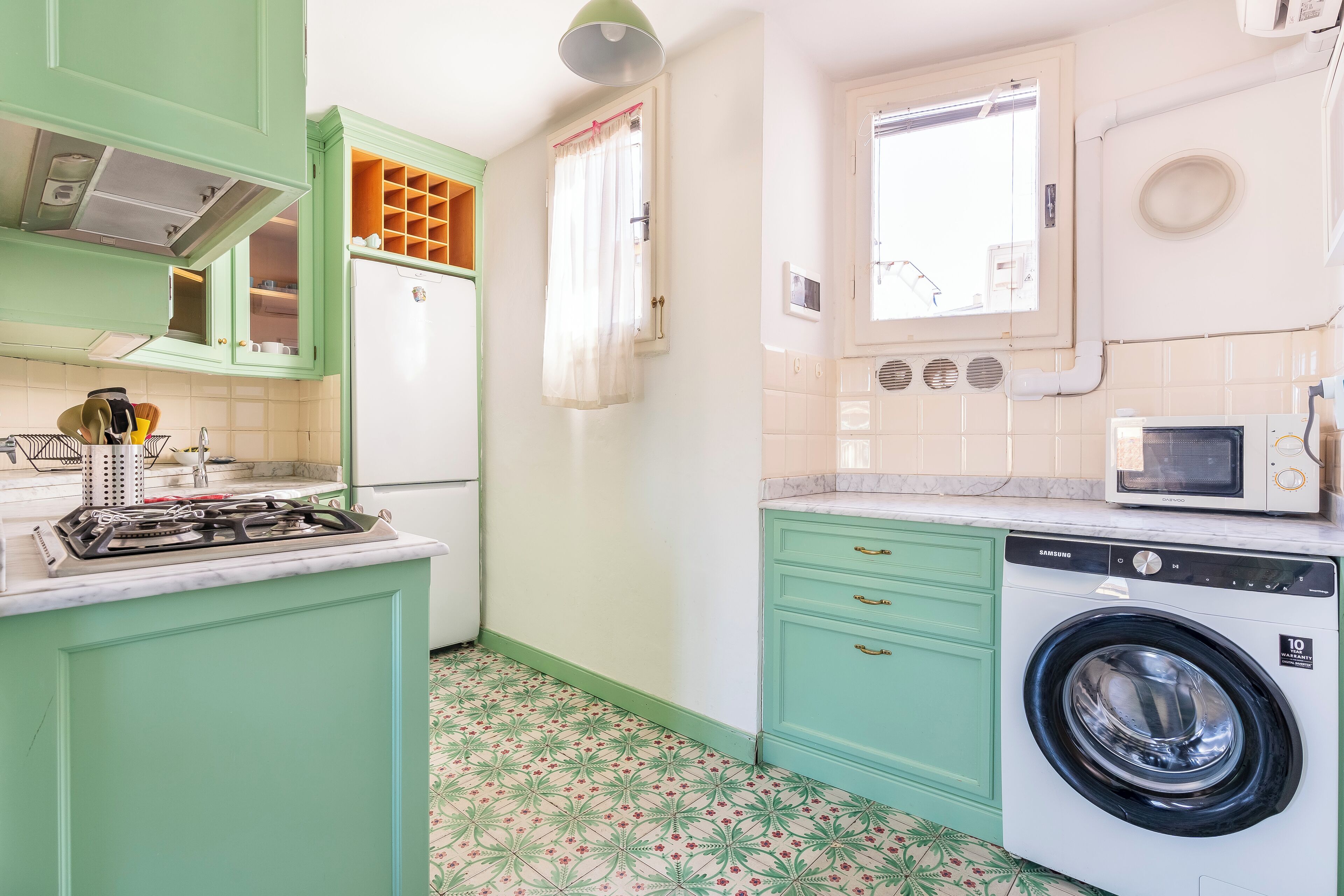 A kitchen with green cabinets, a built-in stove, a microwave, and a washing machine.