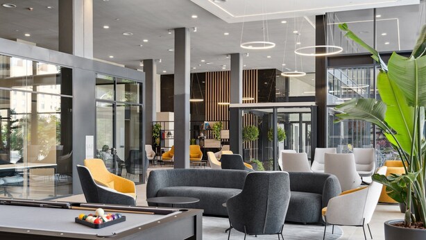 A modern lobby with a pool table, comfortable seating, and a large potted plant. - Truliving Vallecas by Habyt (Madrid)