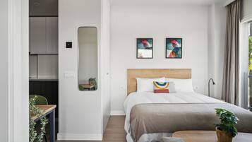 Un dormitorio moderno con cabecera de madera, una cama grande, una mesita de noche y una planta en maceta.