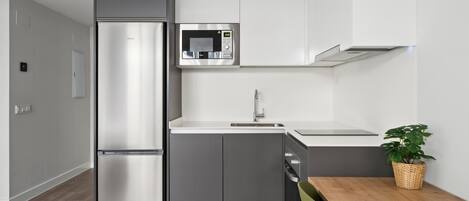 Une cuisine moderne équipée d’un réfrigérateur, d’un four à micro-ondes et d’un évier intégrés.