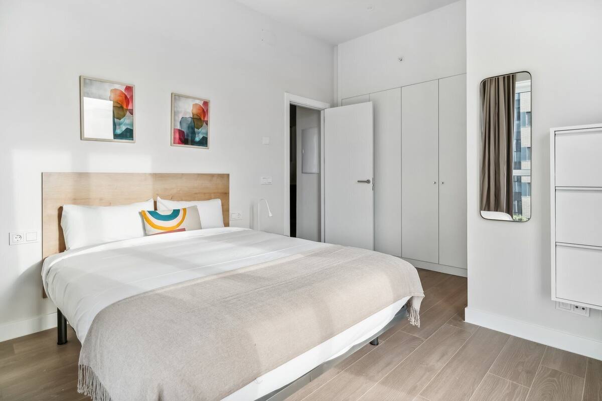 A modern bedroom with a bed, a wardrobe, and two abstract paintings on the wall.