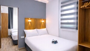 Moderni hotellihuone, jossa on suuri sänky, puinen pääty ja kattovalaisin.