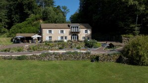A large, two-story building with a balcony, surrounded by a landscaped garden and stone walls. - Maison Spacieuse , Pour Séjours au Calme sur le Plateau des Mille Étangs (La Lanterne-et-les-Armonts)