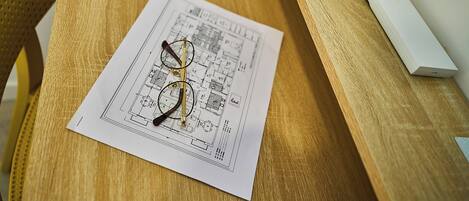 Un plano sobre una mesa de madera con un par de gafas y un dispositivo blanco.
