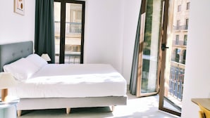 Een slaapkamer met een bed, een raam en uitzicht op gebouwen.