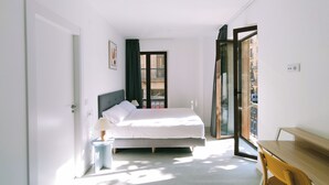 Een moderne slaapkamer met een bed, een bureau en uitzicht op een balkon.