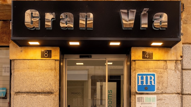 De ingang van Hotel Gran Via, met een glazen deur, nummers 8 en 4, en een bordje waarop staat dat het een hotel is.