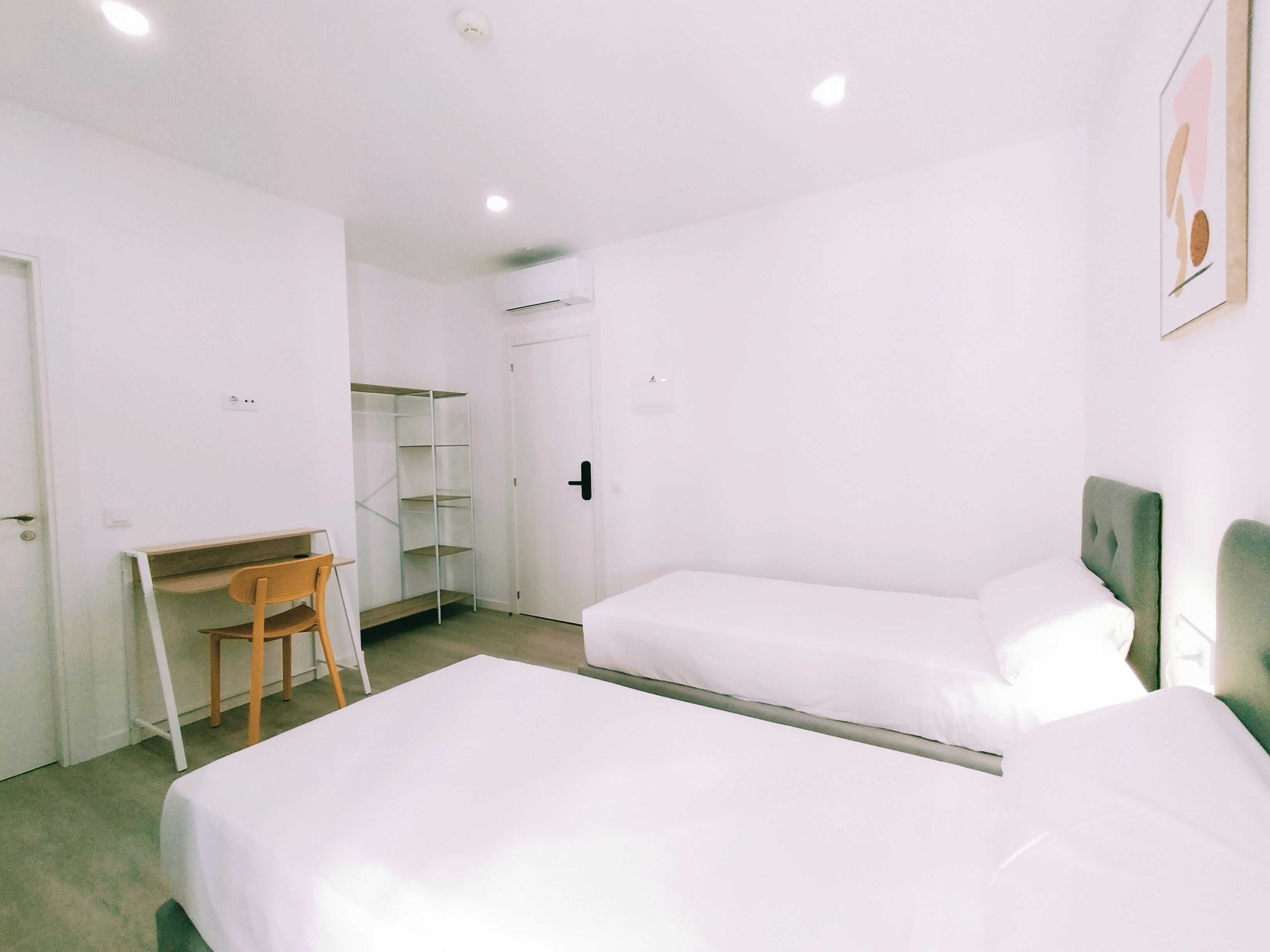 A room with two beds, a desk, and a chair.