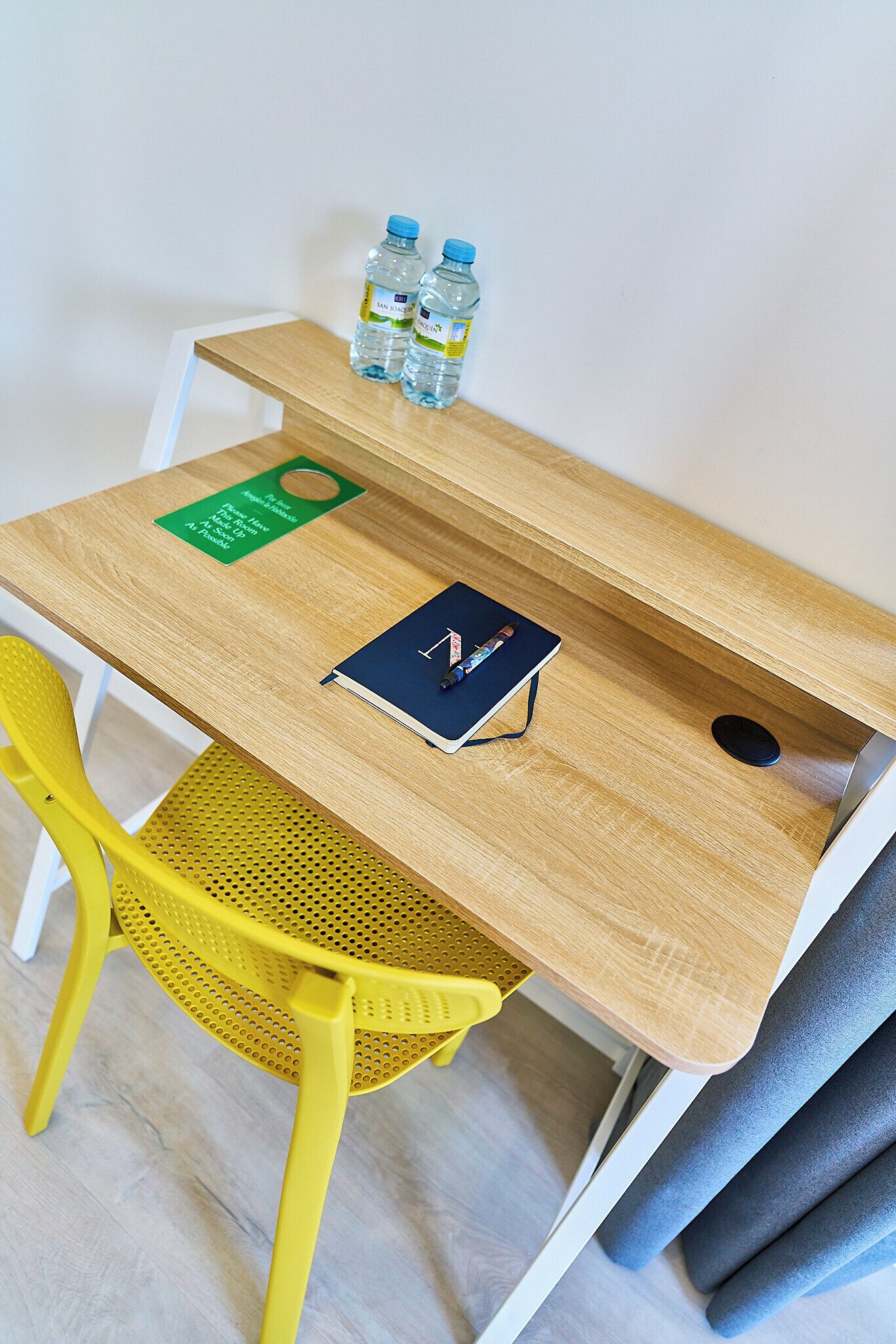 Ein Holztisch mit einem Notizbuch, Stiften und Wasserflaschen.