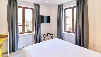 A hotel room with a bed, a TV mounted on the wall, a desk, and a chair.