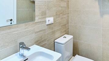 A modern bathroom with a white sink, toilet, and towel rack.