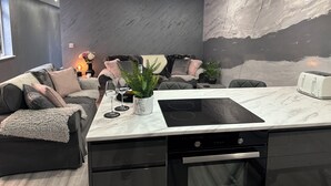 A modern kitchen with a marble countertop, integrated stove, and dishwasher.