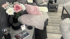 A modern living room with a sofa, a coffee table, and a side table. There is a vase with flowers on the coffee table.