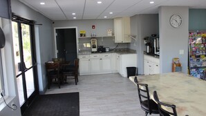 A modern kitchen with white cabinets, a marble countertop, and a dining area with a table and chairs. - Riverfront Inn (Conway)