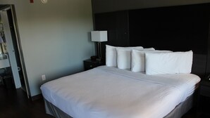 A neatly made bed with white linens in a hotel room.