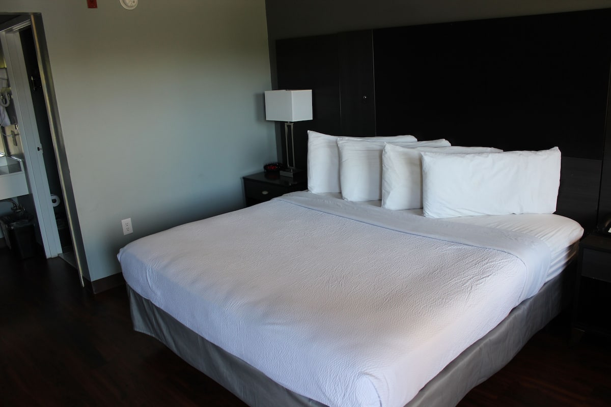 Un lit bien fait, avec du linge de lit blanc, dans une chambre d'hôtel.
