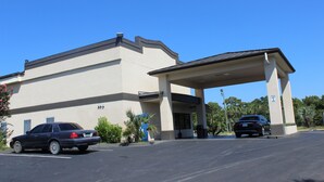 A building with a covered entrance and two cars parked in front. - Riverfront Inn (Conway)