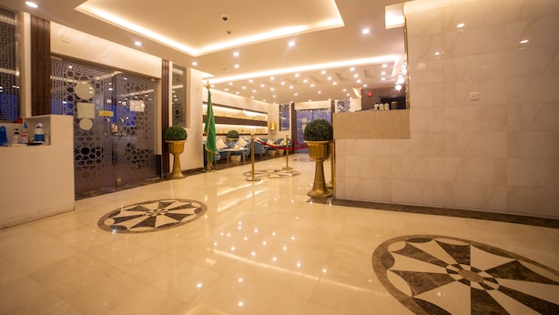 A modern hotel lobby with a marble floor, a reception desk, and a seating area with a blue sofa.