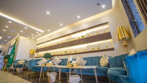 A modern lobby with a blue sofa set, a reception desk, and a decorative wall with shelves.