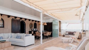 Un salón espacioso con un sofá blanco, una mesa de comedor con sillas y un área de estar con sillones.