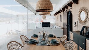 Un comedor moderno con una mesa de madera dispuesta para seis personas, rodeada de sillas de mimbre.