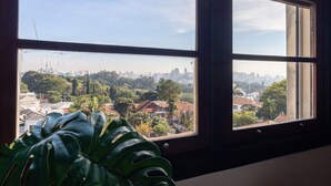A window with a view of a cityscape, including buildings and greenery. - Apartamento Amplo Prox HC São Paulo (São Paulo)