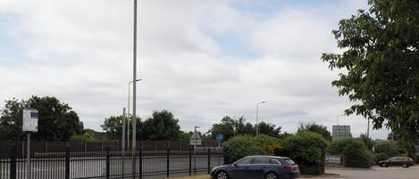 A parking area with a car, a fence, and a sign indicating parking regulations.