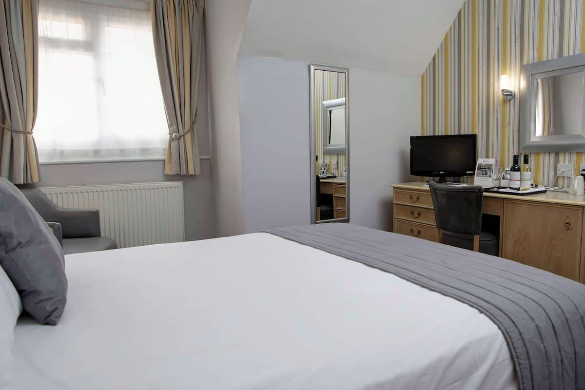 Une chambre d’hôtel équipée d’un lit, d’un bureau, d’une chaise, d’une télévision et d’un miroir.