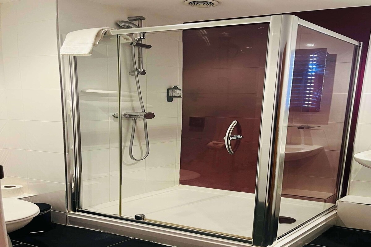 A modern bathroom with a glass-enclosed shower, a white sink, and a toilet.
