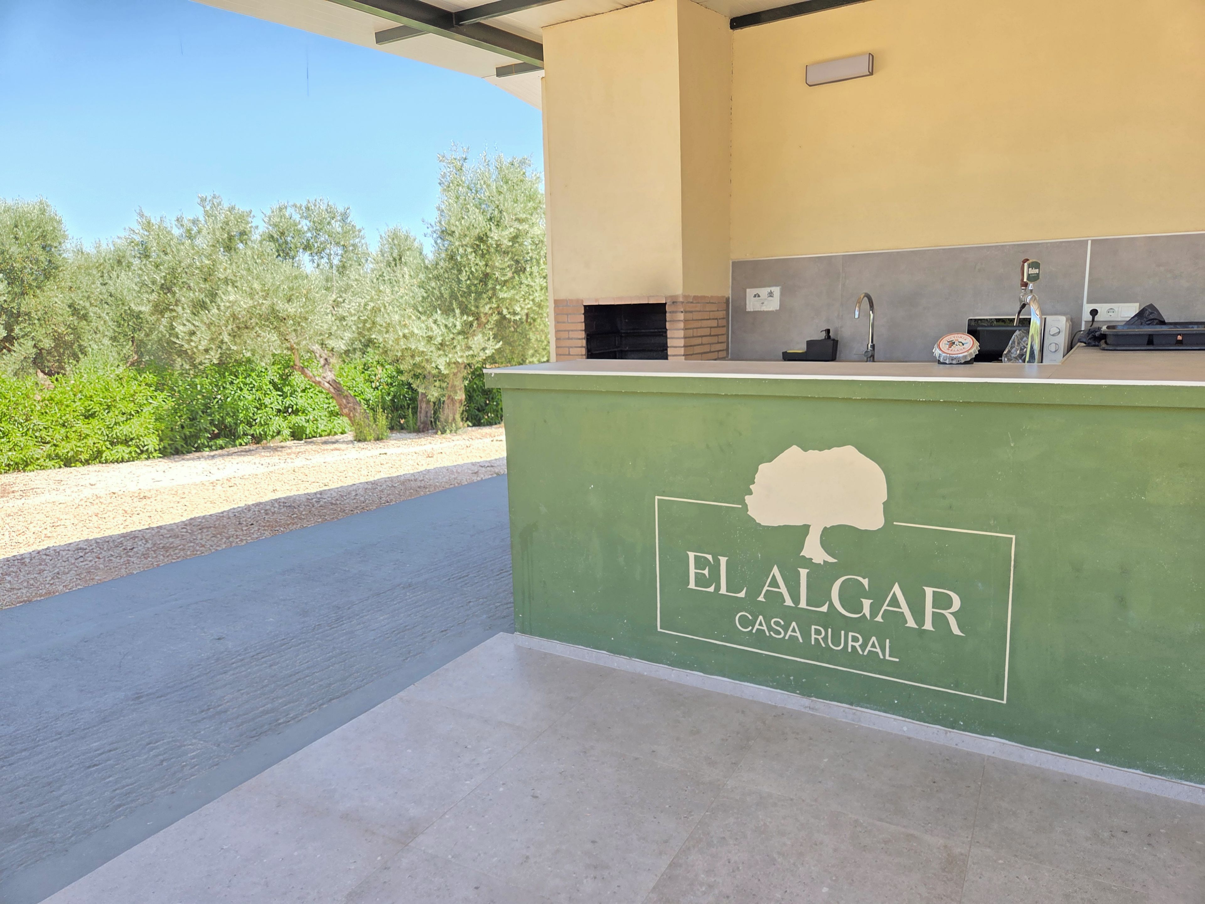 Un espace d’accueil avec un comptoir vert où figure le logo « EL ALGAR CASA RURAL ».