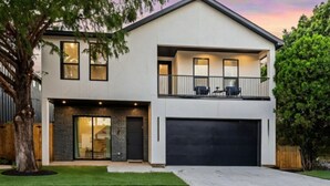A two-story modern house with a garage, a balcony, and a large tree in the front yard. - Beautiful, Cozy, Contemporary 4BR near Downtown Dallas
 (Dallas)
