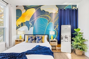 A bedroom with a large bed, two bedside tables with lamps, a mirror, a potted plant, and a wall with a leaf pattern. - Beautiful, Cozy, Contemporary 4BR near Downtown Dallas
 (Dallas)