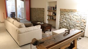 A living room with a sofa, coffee table, and a stone wall. - Valèt guesthouse, four rooms and sleeps 12, half an hour from Alba (Moasca)
