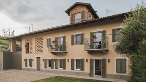 A two-story building with balconies, a tiled roof, and a small garden area. - Valèt guesthouse, four rooms and sleeps 12, half an hour from Alba (Moasca)