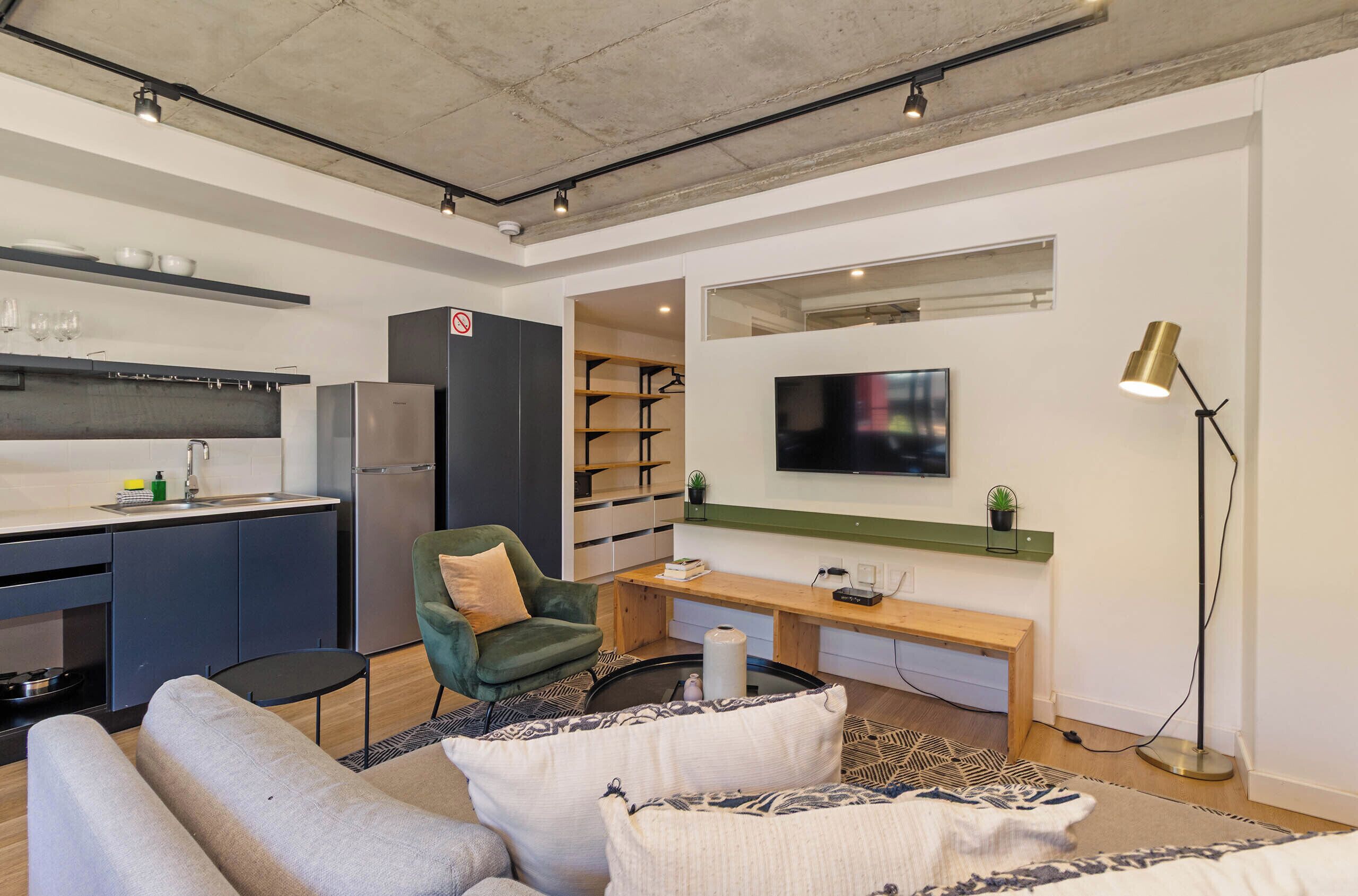 A modern living space with a kitchen, seating area, and a flat-screen TV.