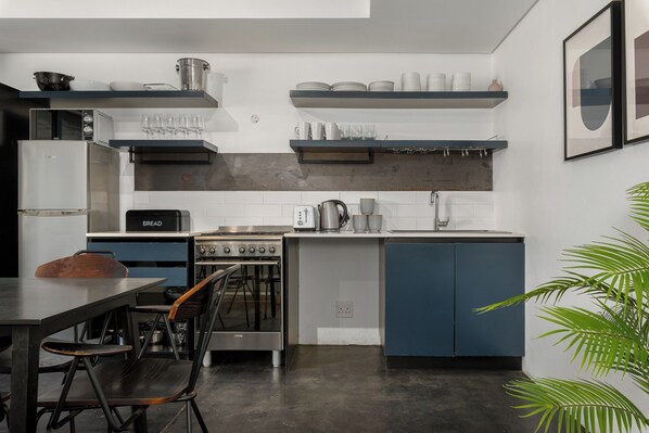 Une cuisine moderne équipée d’un four encastré, d’une machine à café et d’un coin repas avec une table et des chaises.