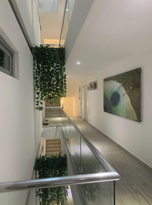 Staircase leads to an upper level, surrounded by a clean and contemporary space with a piece of abstract art and a hanging plant.