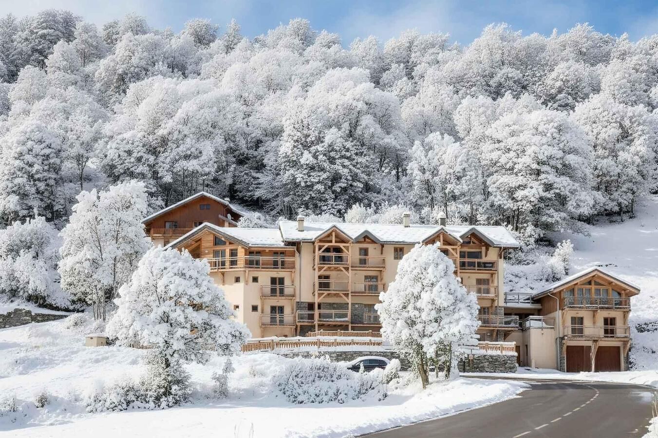 A multi-story lodge with a wooden exterior, surrounded by snow-covered trees and a clear sky.