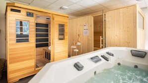 Una sauna amb parets de fusta, una porta de vidre i una banyera d'hidromassatge amb panells de control.
