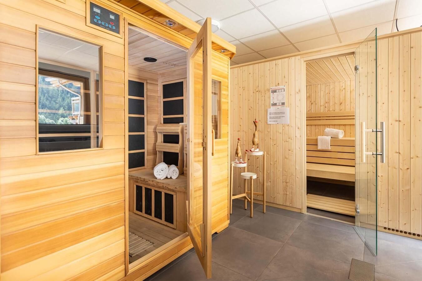 Een sauna met houten wanden en banken, een bedieningspaneel en handdoeken op de banken.