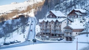 A snow-covered mountain lodge with multiple balconies and a ski lift visible in the background.