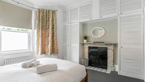 A hotel room with a bed, a fireplace, a window with curtains, and built-in wardrobes. - Elegant GetAway House in Vibrant Clapham Juction - Pass the Keys (London)